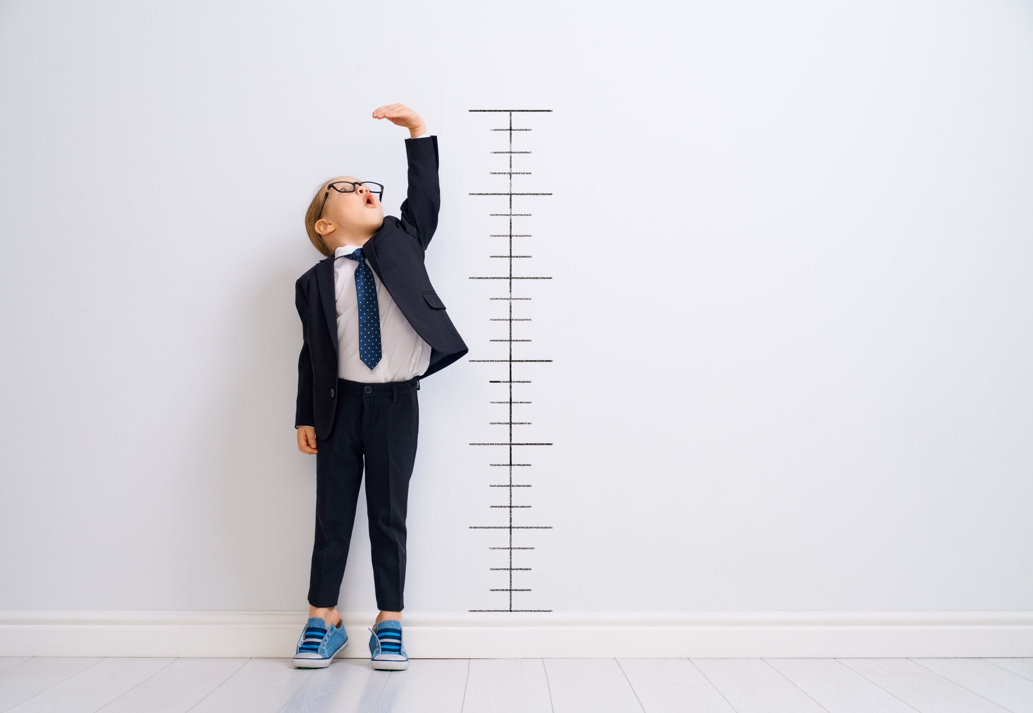 Imagen de un niño midiendo su altura en una pared. Simboliza los dolores de crecimiento frecuentes en la niñez y la adolescencia