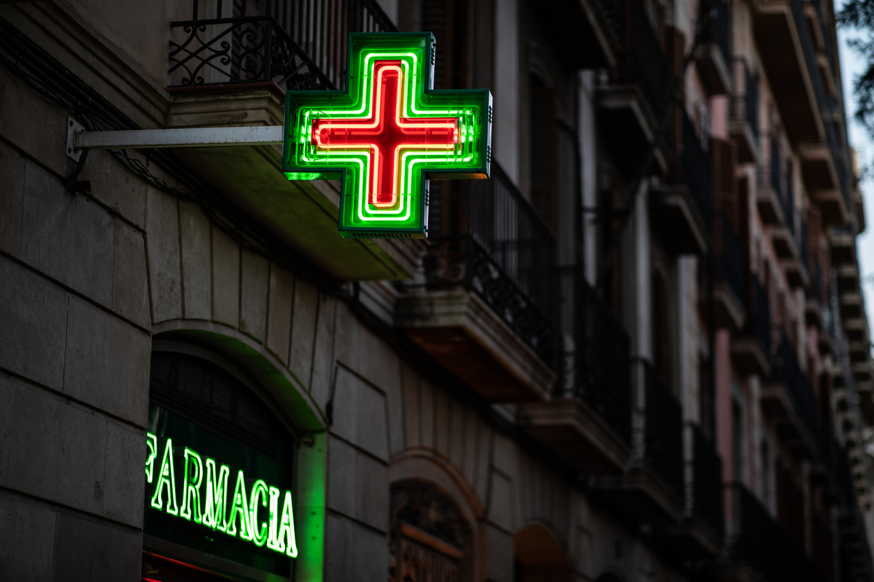 Pharmacy signs illuminated at night on spanish architecture facade with copy space