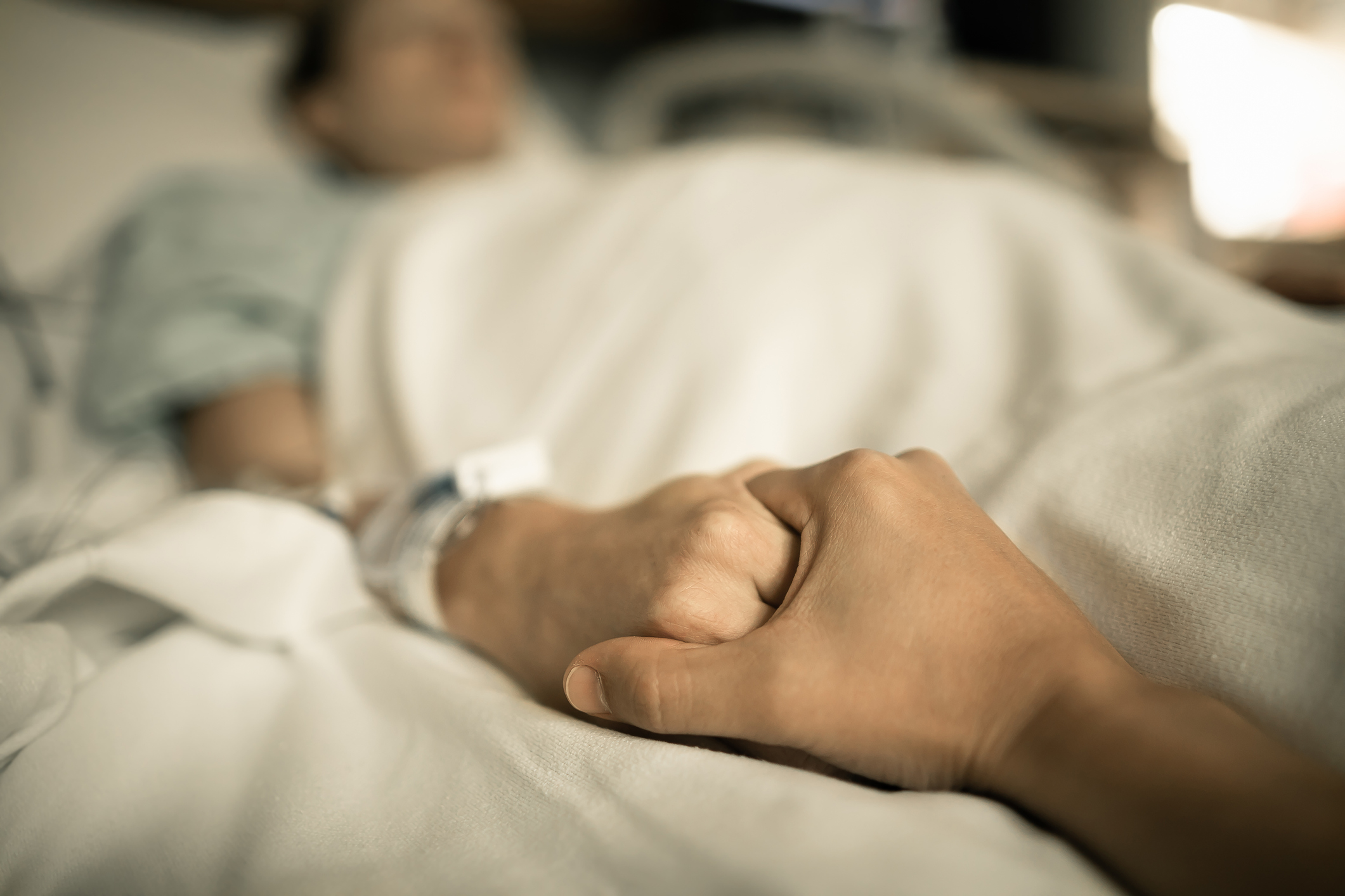 Man holding hand, giving support and comfort to woman, loved one sick in hospital bed.