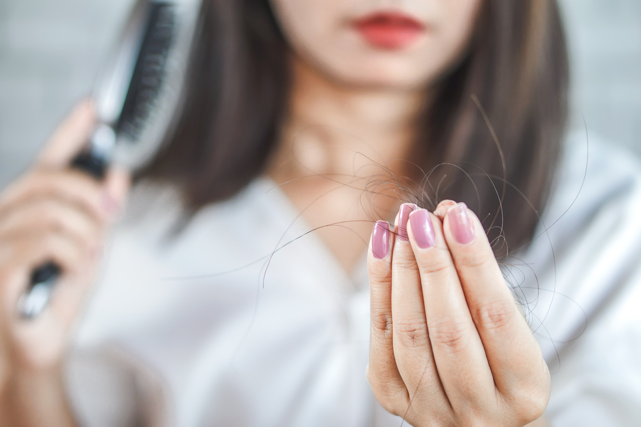 closeup woman hand holding hair fall from hairbrush