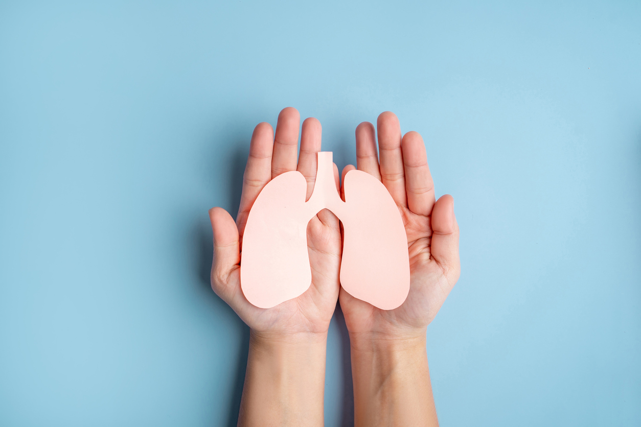 Human hands holding healthy lung shape made from paper on light blue background. World lung day.