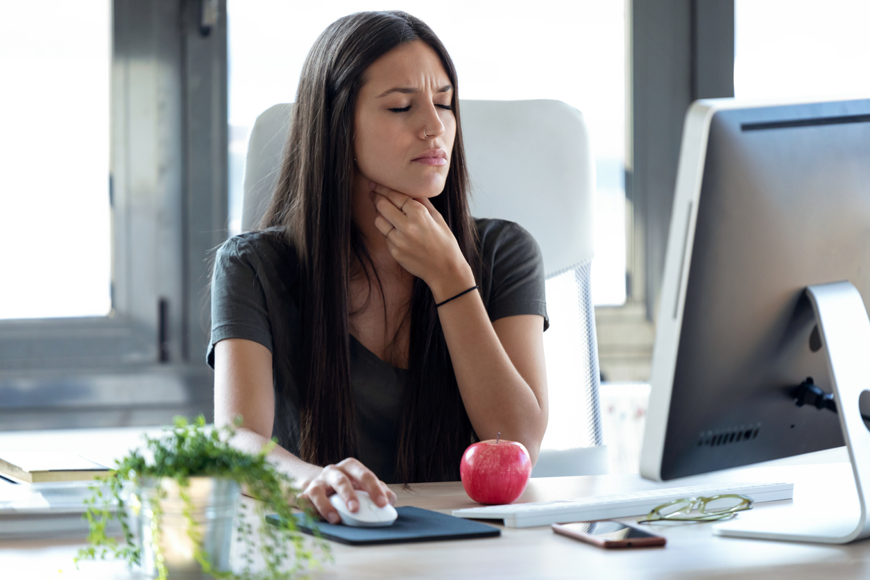 mujer de negocios que padece dolor de garganta en su trabajo