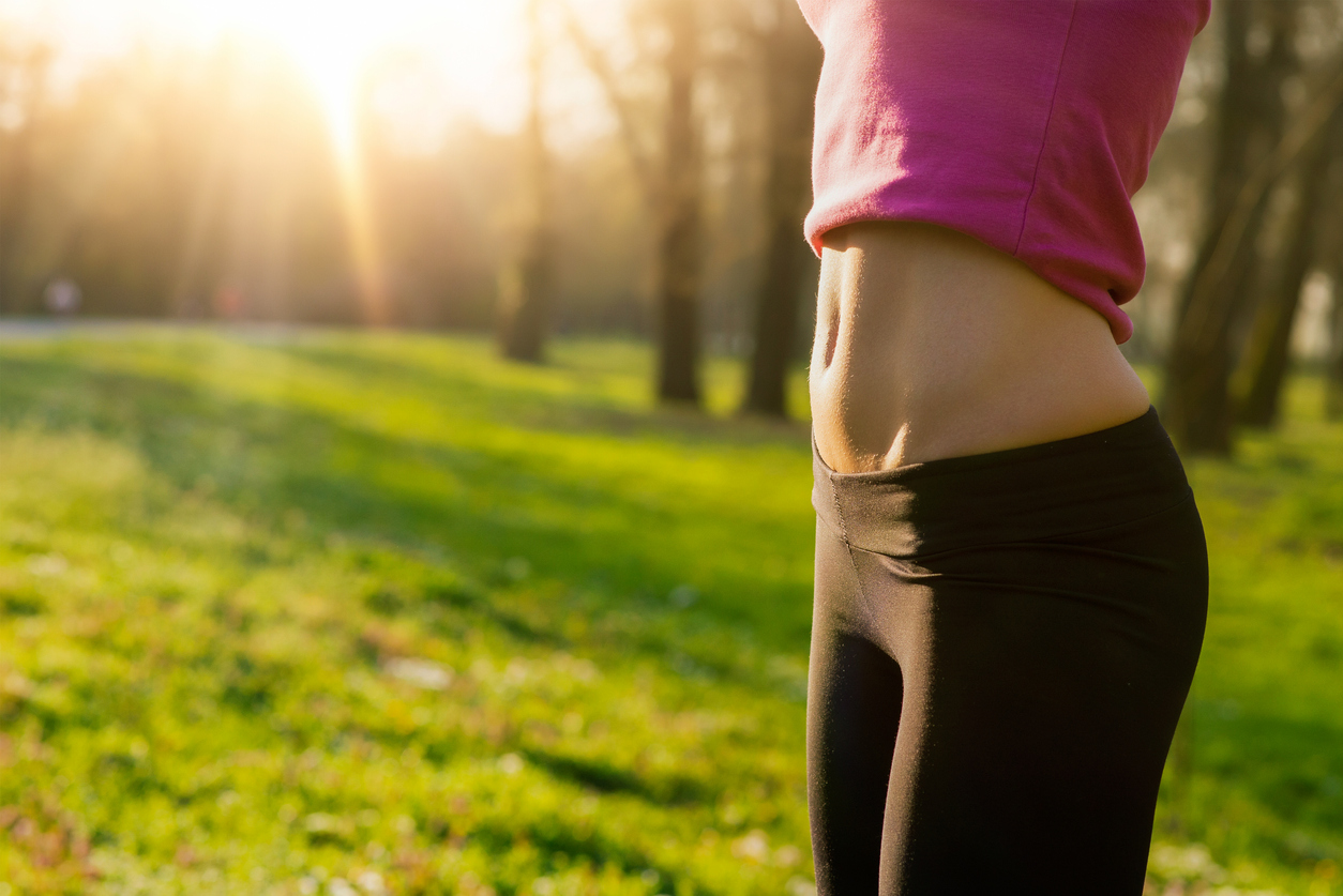 Young fit woman's belly outdoors in summer